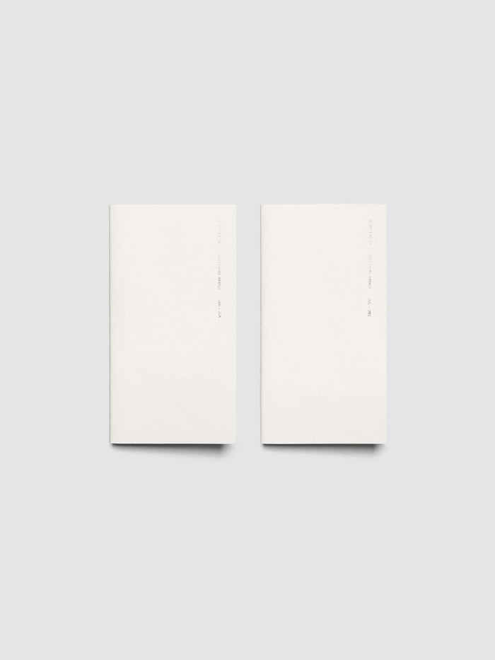 Both 2027 Dated Travel Notebooks in Pocket Plus size displayed side by side, showing the off-white covers with silver foil text for the Jan–Jun and Jul–Dec volumes