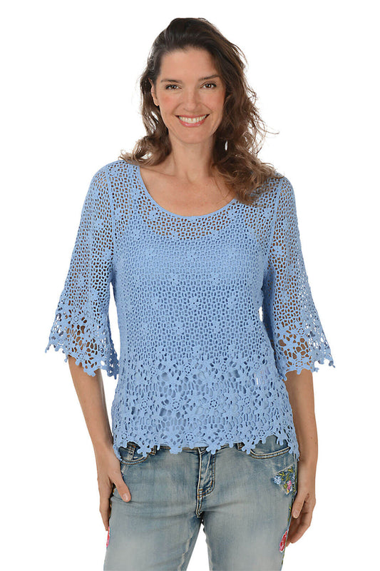 Woman wearing a blue crochet top and jeans on a white background.