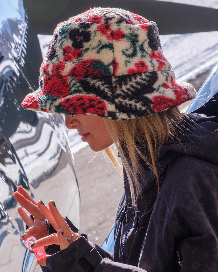 Person wearing a colorful floral-patterned bucket hat outdoors.